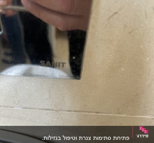 ברז נירוסטה עם השתקפות של יד